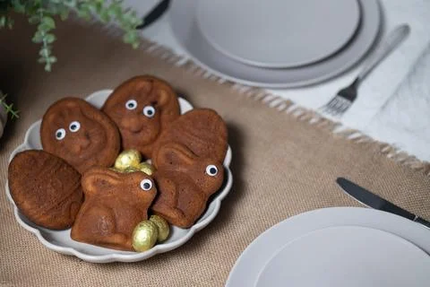 Close-up of Easter muffins shaped as bunnies and eggs with eyes, chocolate eggs Stock Photos