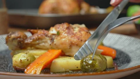 Close-up of eating with fork and knife freshly roasted chicken with vegetables. Stock Footage 145119032