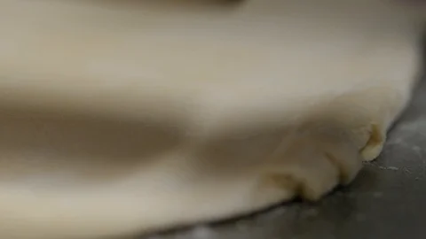 Close up edge of dough being flattened by rolling pin Stock Footage 93369649