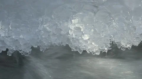 Close up of edge of ice at a creek with fast running water Stock Footage 49701378