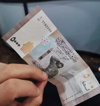 A close-up editorial view of a hand holding a five hundred Syrian pound Stock Photos