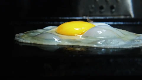 Close up egg falling on griddle and completed cooked real time Stock Footage 247582862