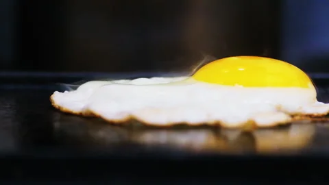 Close up egg fried on a black griddle with smoke SLOWMO 60 Stock Footage 246552860