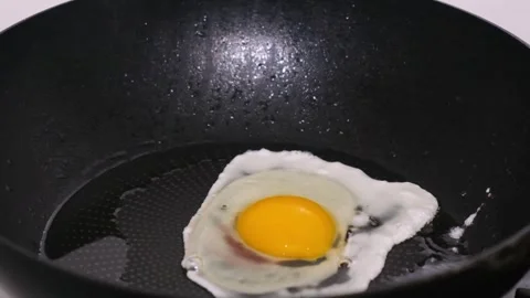 Close-up of an egg sizzling in a pan, shot in slow motion. Cooking concept Stock Footage 253079059