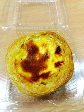 Close up Egg tart in plastic box putting on wooden table. Top view of dessert Stock Photos