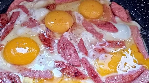 Close-up of eggs and sausage being fried in a frying pan. Stock Footage 254981751