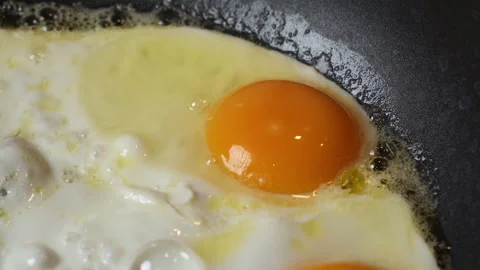 Close up of eggs being fried in a black pan in a home kitchen. Stock Footage 301542967