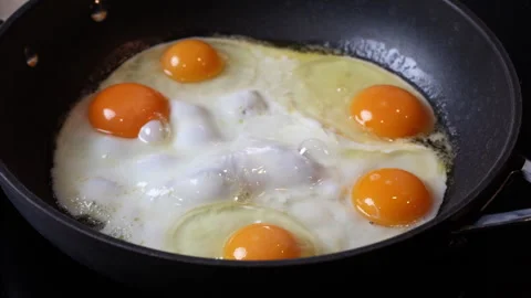 Close up of eggs being fried in a black pan in a home kitchen. Video stock 301543206