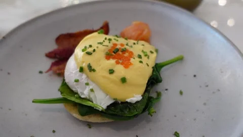 Close up of eggs benedict served with bacon, spinach and hollandaise sauce. Stock Footage 301368009