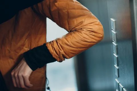 Close up of elbow pressing the button elevator during coronavirus pandemic covid Foto stock