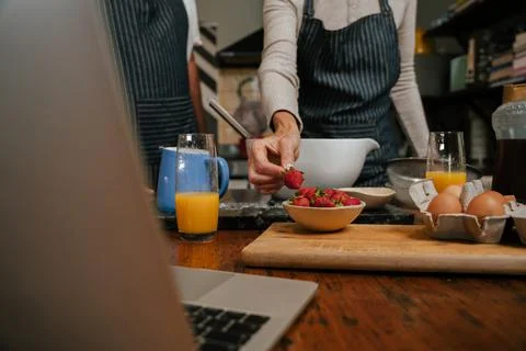 Close up of elderly couple baking in kitchen with laptop Stock Photos