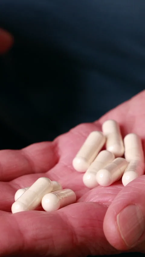 Close-Up Of Elderly Hands Opening To Reveal White Capsules On The Palm, With A M Stock-Footage 322979025