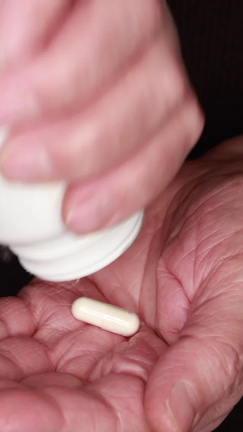Close-Up Of Elderly Hands Shaking Out A Single Capsule From A Medicine Bottle, H Video stock 322979017