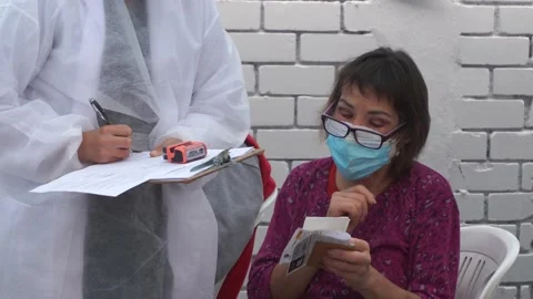 Close-up of an elderly lady sitting chatting with a standing nurse Видео 154961565