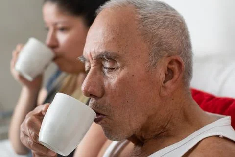 Close up of elderly man drinking coffee showing careful movement and aging .. 库存照片