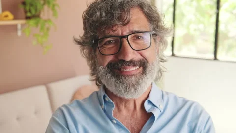 Close-up of an elderly man looking at the camera with smile in cozy living-room Stock Footage 253928552