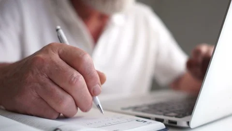 Close-up, an elderly man makes notes with a pen in a notebook while working with Stock Footage 120796150