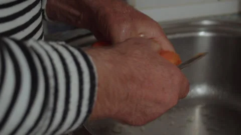 Close-up, elderly man peeling carrots with a knife over kitchen sink Vidéo 337118278