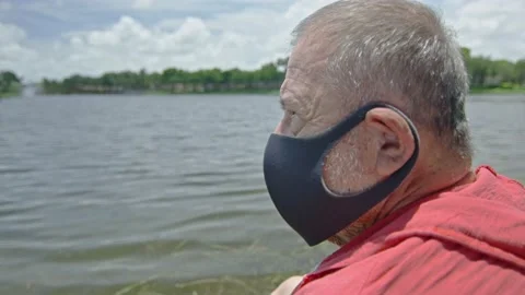 Close-up of elderly man wearing a face mask in front of lake Stock Footage 131058608