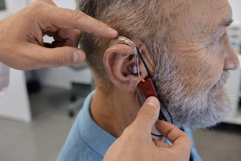 Close-up of elderly man's ear with hearing aid and special equipment to adj.. Foto stock