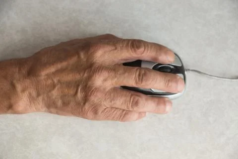 Close-up of an elderly man's hand on a computer mouse. older people are learn Stock Photos