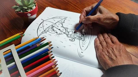 Close-up of an elderly man's hand holding a colored pencil over a paint-by-nu Stock Photos