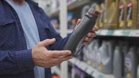 Close-up of an elderly man's hands holding engine oil in a supermarket. Stock Footage 252080075