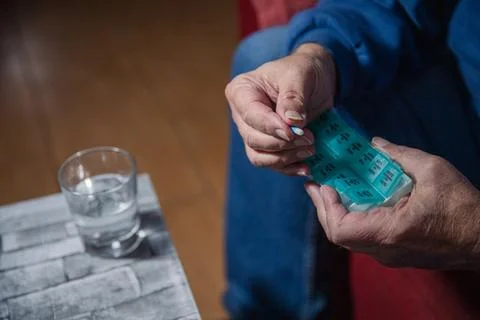 Close-up of an elderly man's hands taking medicines from his medicament dis.. Foto stock