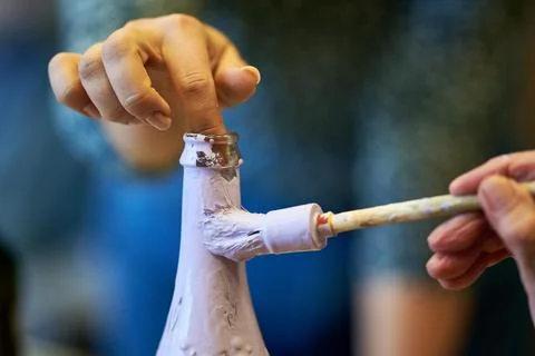 Close up of an elderly person's finger holding a glass bottle while it is bei Photos