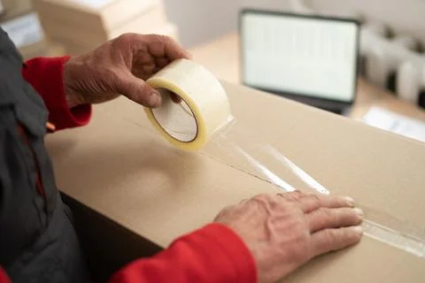 Close up of elderly postal worker hands packing cardboard parcel box for sh.. Stock Photos