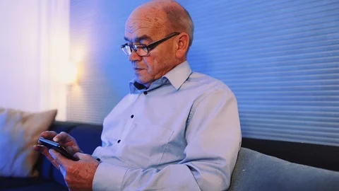 Close up of elderly using his smart phone in horizontal position at home Stock Footage 99015329