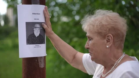 Close-up. An elderly woman posts a paper notice about a missing elderly man on a Stock Footage 273755818