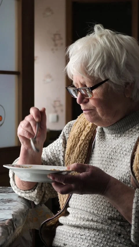 Close-up of an elderly woman who eats porridge. The old woman eats food. Social Stock Footage 270483427