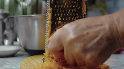 Close-up, elderly woman's hand grating a pumpkin on a kitchen grater to make a Stock Footage 337120756