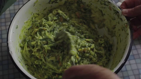 Close-up, elderly womans hand kneading vegetable pancake dough in metal bowl Stock Footage 318554267