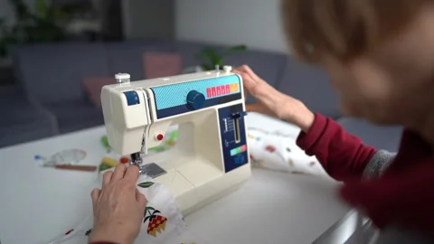 Close-up of an elderly woman's hand sews textiles with a sewing machine. Home Stock Footage 148333732