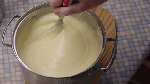 Close-up, elderly woman's hand stirring boiled cake cream in metal saucepan Stock Footage 304694869