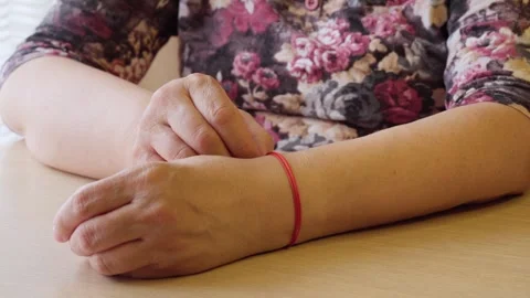 Close-up of an elderly woman's hand touching the red thread on her wrist. Stock Footage 275081593