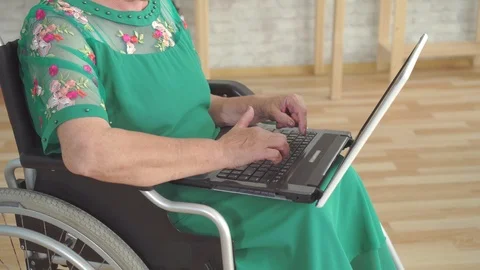 Close up of an elderly woman's hand typing on a laptop and sitting in a Stock Footage 113451067