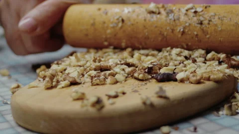 Close-up of elderly womans hands crushing nuts on kitchen board to make pumpkin Stock Footage 318853139