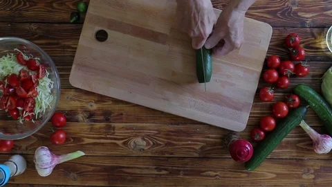 Close up of elderly woman's hands cutting cucumber for salad, top view Stock Footage 90774738