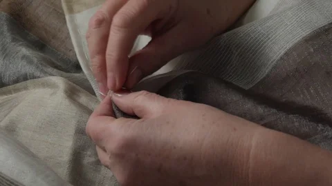 Close-up of an elderly woman's hands hem curtains Stock-Footage 125584756