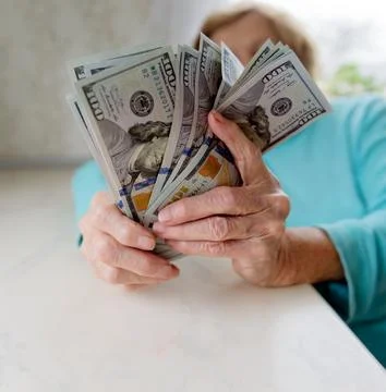 Close-up of an elderly woman's hands holding money in 100 dollar bills Stock Photos