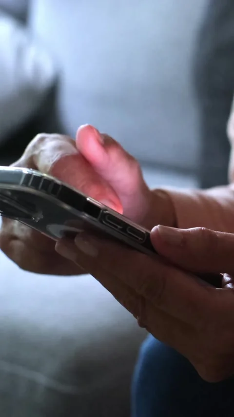 Close-up of an elderly woman's hands using a mobile phone, her thumb scrolling Stock Footage 344782677