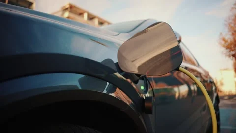 Close up electric car charging cable connected to vehicle port during dayti.. Stock Footage 339458575
