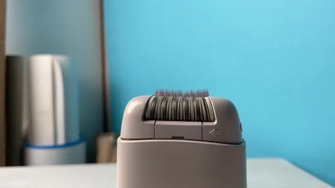 Close-up of an electric epilator in operation,rollers and tweezing head mov.. Stock Footage 329916249