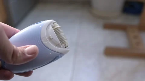 Close-up of an electric epilator turning on with buzzing motor sound, showing Stock Footage 319503274