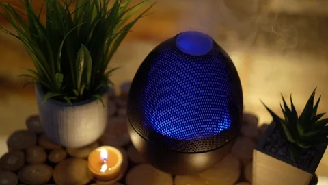 Close up of electric oil diffuser lamp, candles on wooden table in room. Video stock 129296479