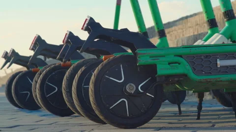 Close-up, electric scooters stand in a row in the town square at sunset Stock Footage 201827694