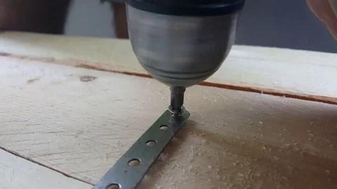 Close up electric screwdriver screws screw into metal on wooden board, hand Vídeos de archivo 77401437